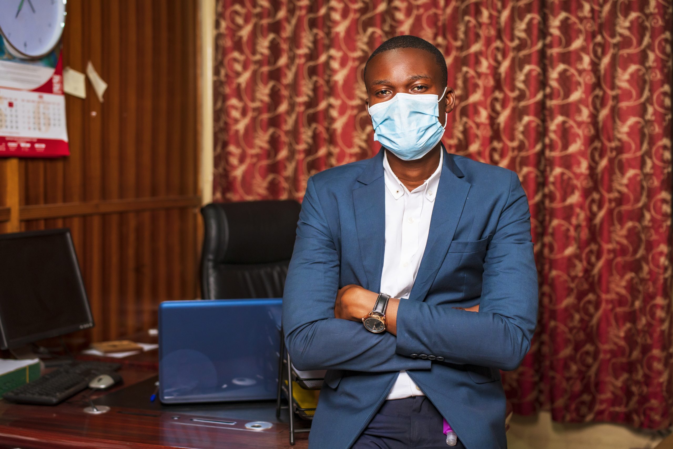 A young African American businessman wearing a protective mask in his office
